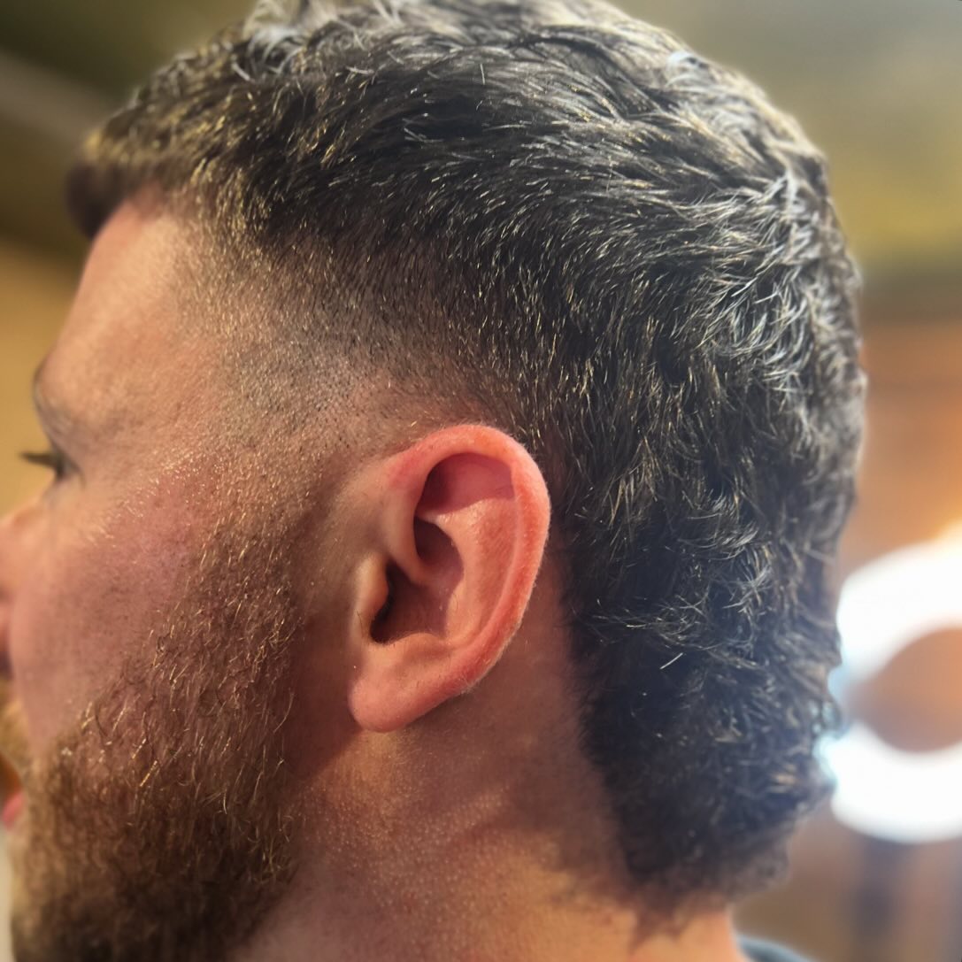 A textured cut with a fade into a full beard, side view